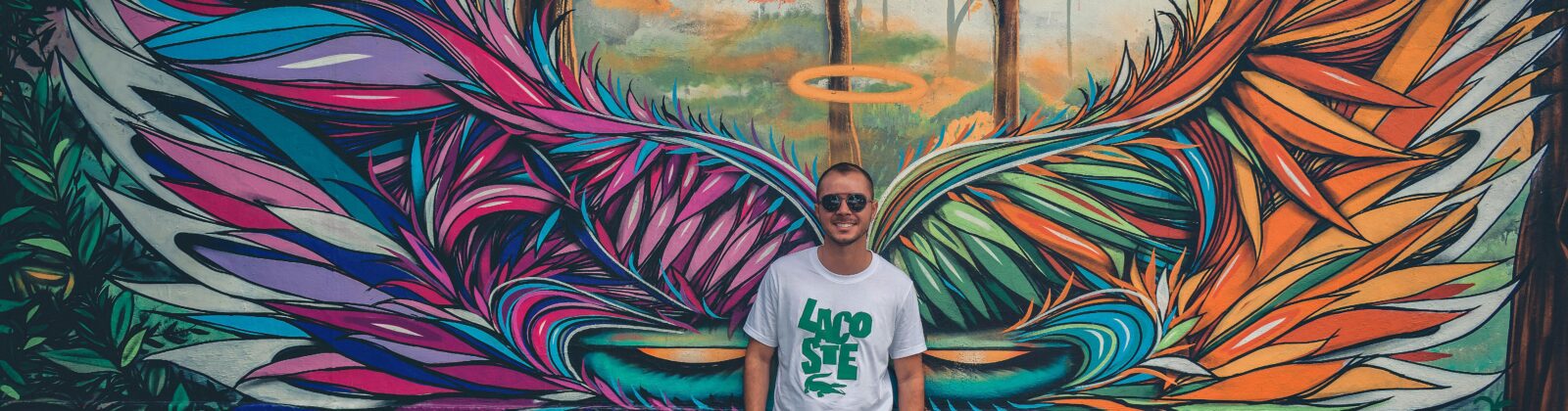 Man in t-shirt in front of mural with angel wings